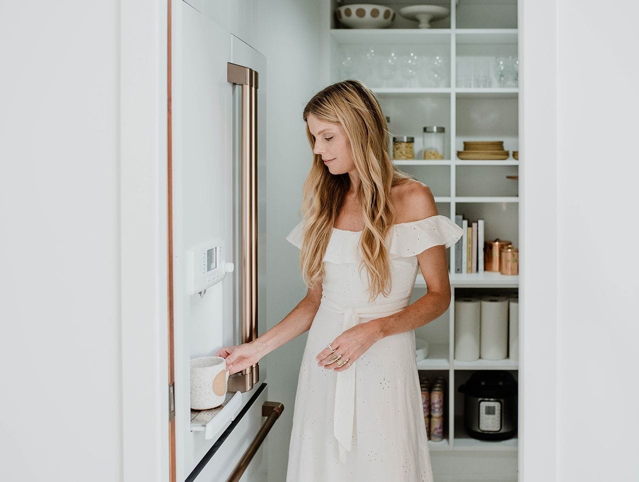 Interior designer Sarah Sherman Samuel stands in front of a clean customized pantry by California Closets